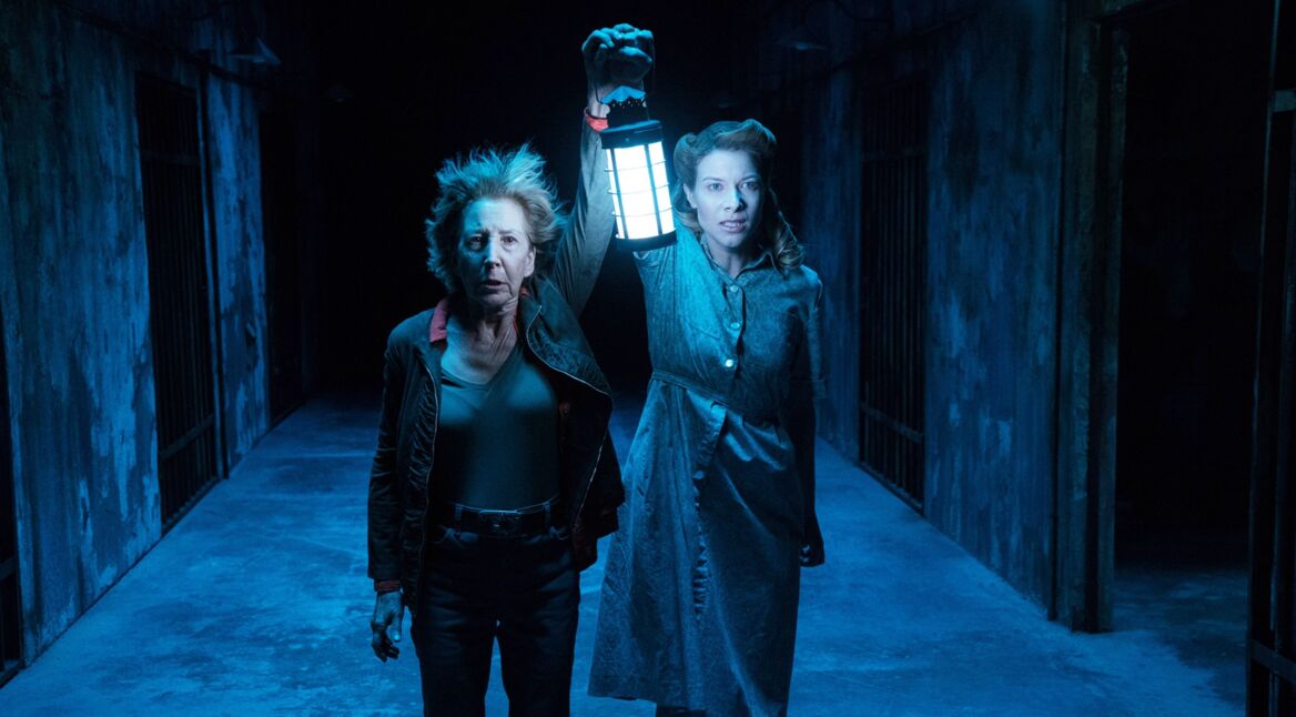 Zwei Frauen mit Laterne in einem dunklen Gang