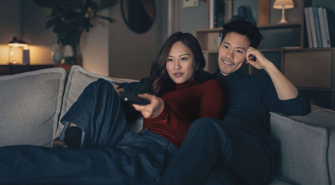 Mann und Frau sitzen gemeinsam auf dem Sofa und schauen einen Horrorfilm