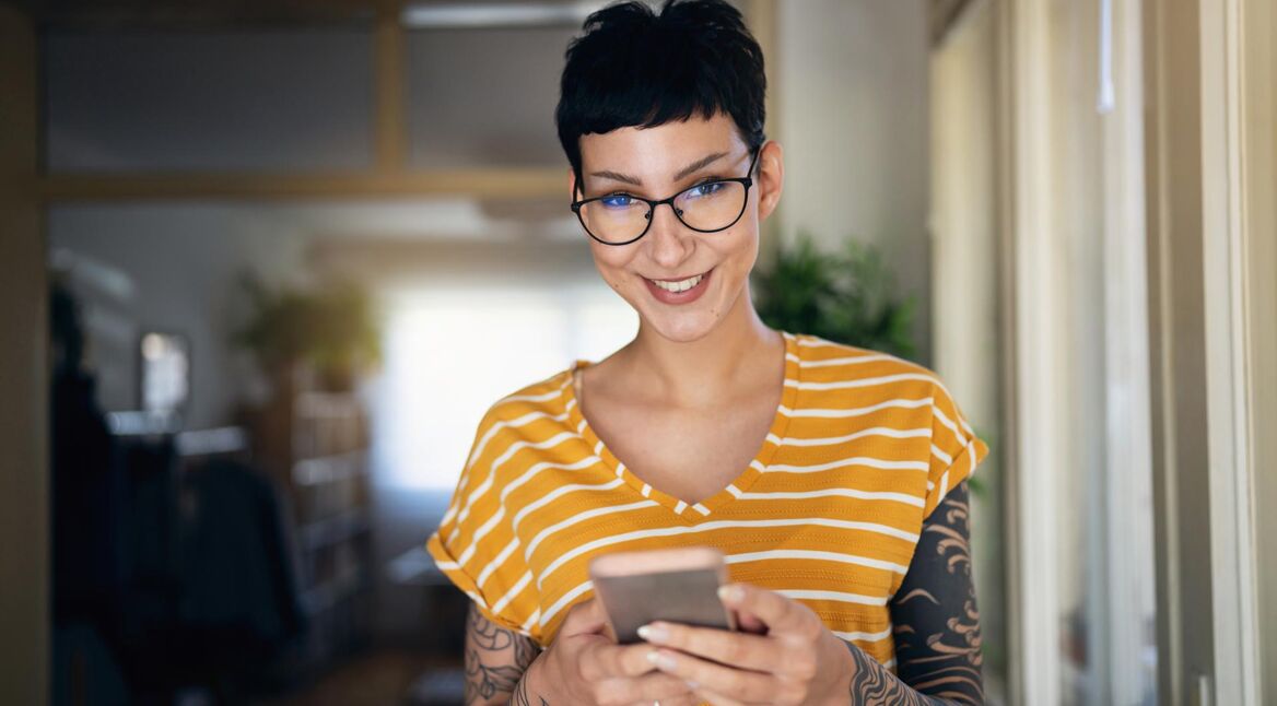 Frau mit kurzen Haaren und Brille hält ein Smartphone in der Hand