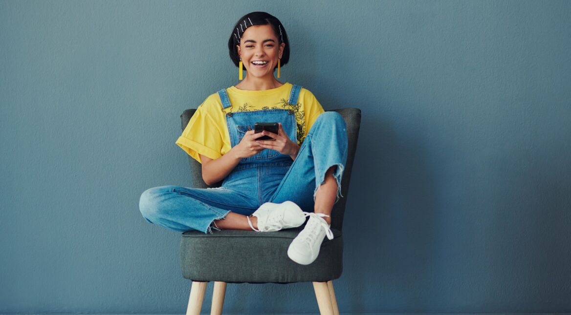 Junge Frau auf Stuhl mit Smartphone