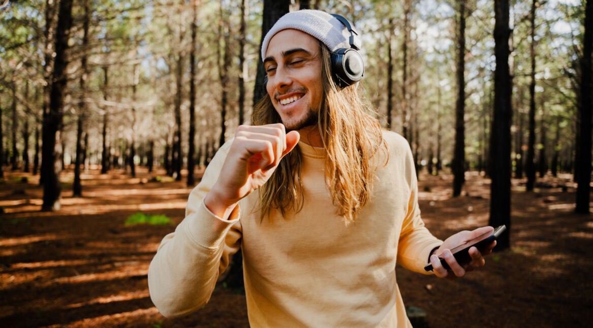 Junger Mann hört via Tidal Musik im Wald