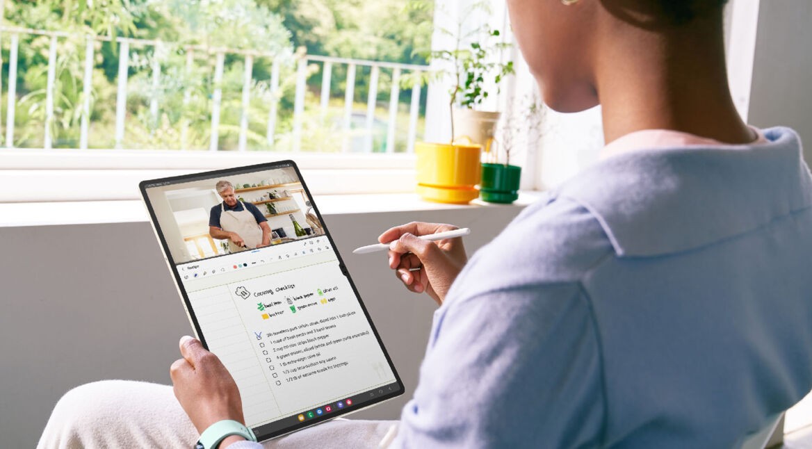 Eine Frau hält ein Tablet in der Hand und arbeitet mit einem Stylus darauf.