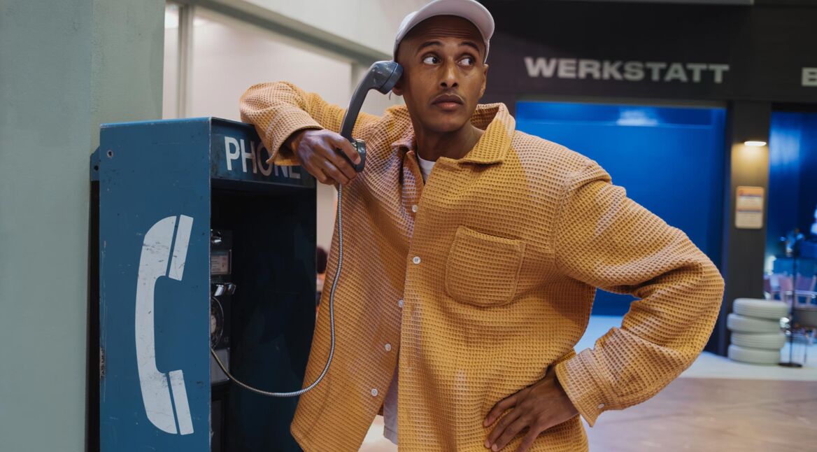 Teddy Teclebrhan steht an einer Telefonzelle