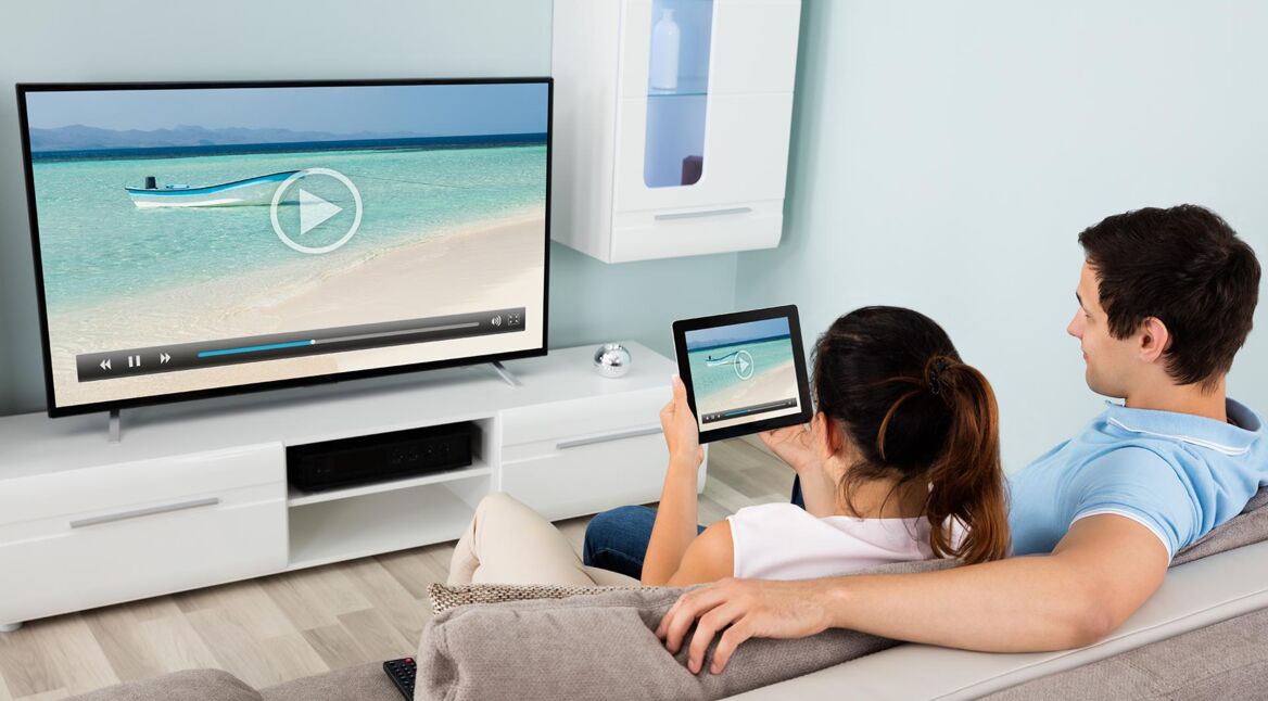 Ein Paar streamt mit einem iPad einen Film auf den Fernseher