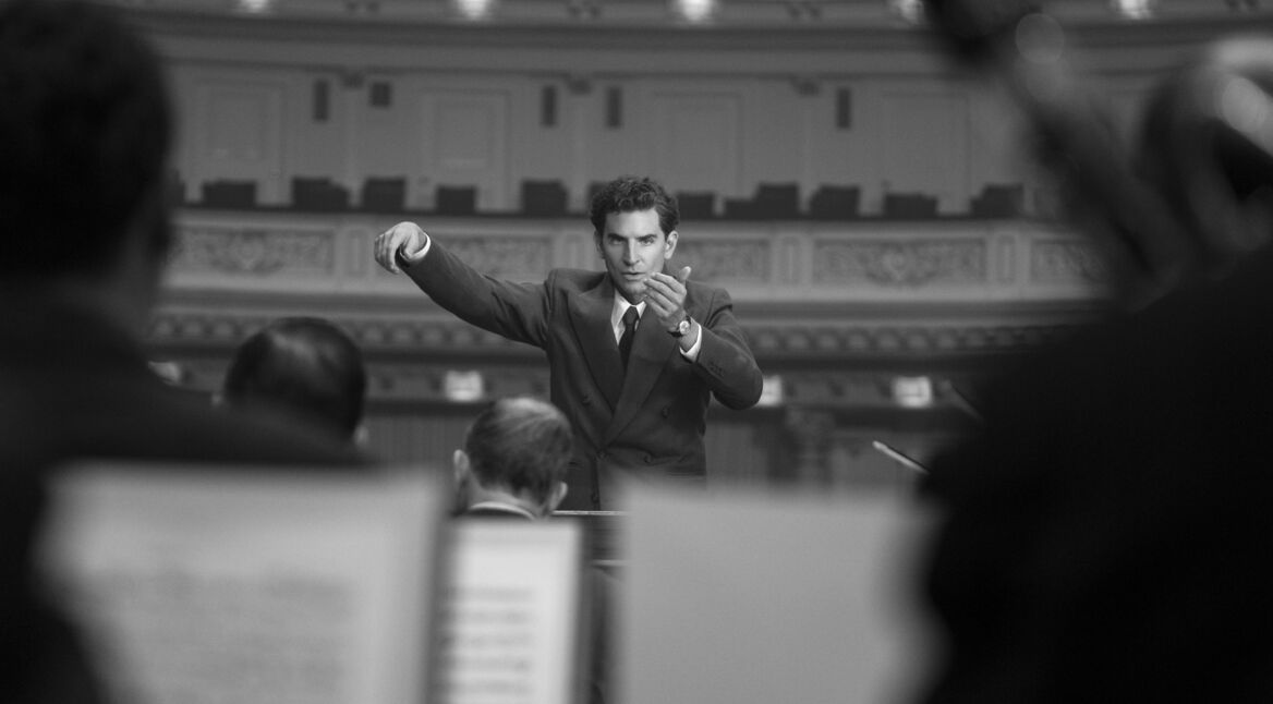 Bradley Cooper als Leonard Bernstein beim Dirigieren eines Orchesters im Film Maestro