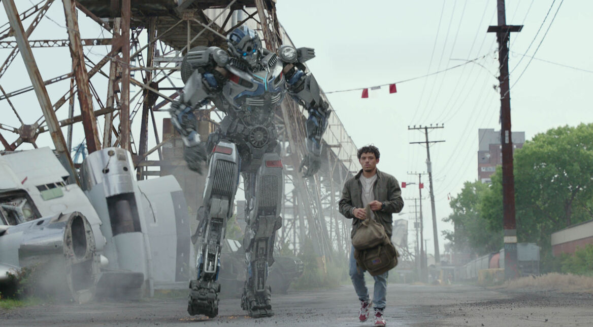 Noah (Anthony Ramos) und Transformer Mirage laufen nebeneinander eine Straße entlang im Film Transformers: Aufstieg der Bestien