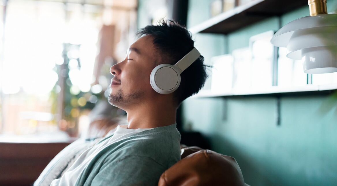 Ein junger Mann hört auf der Couch ein Hörbuch