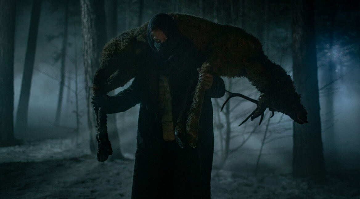 Szenenbild aus der Serie "Die Kreatur". Vermummter Mann trägt Rehbock