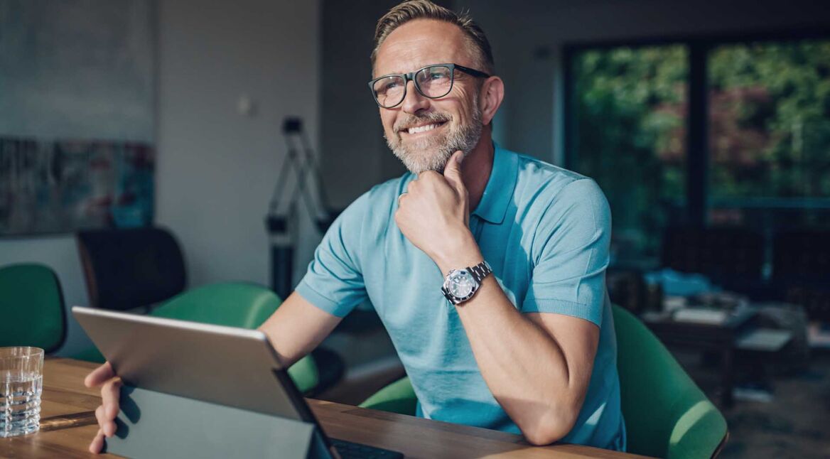 Ein Mann sitzt am Tisch mit seinem Tablet