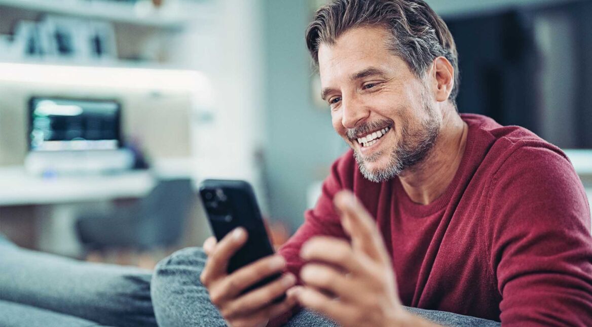 Lächelnder Mann bei einem Videoanruf mit seinem Smartphone in der Hand