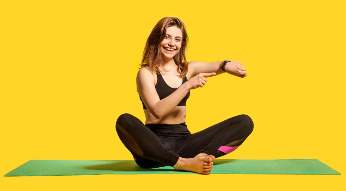 Frau auf Yogamatte mit Fitnesstracker