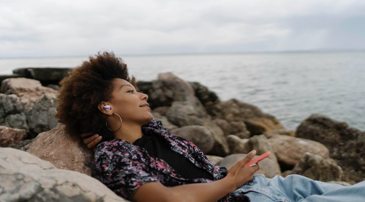 Junge Frau mit In-Ears am Wasser