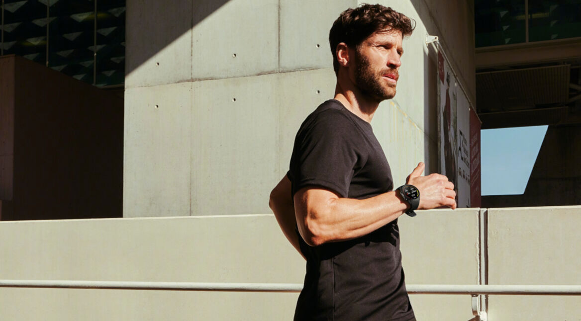 Mann läuft in der Stadt der Sonne entgegen mit OnePlus Watch 2 am Handgelenk