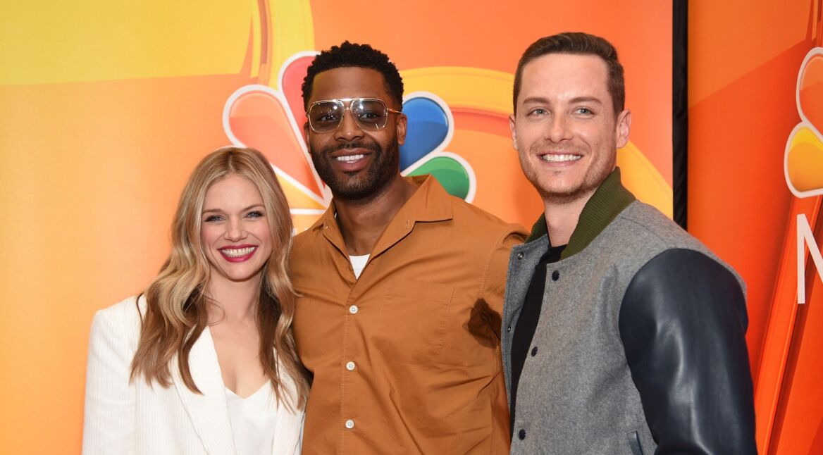 Drei Schauspieler posen vor dem NBC-Logo.