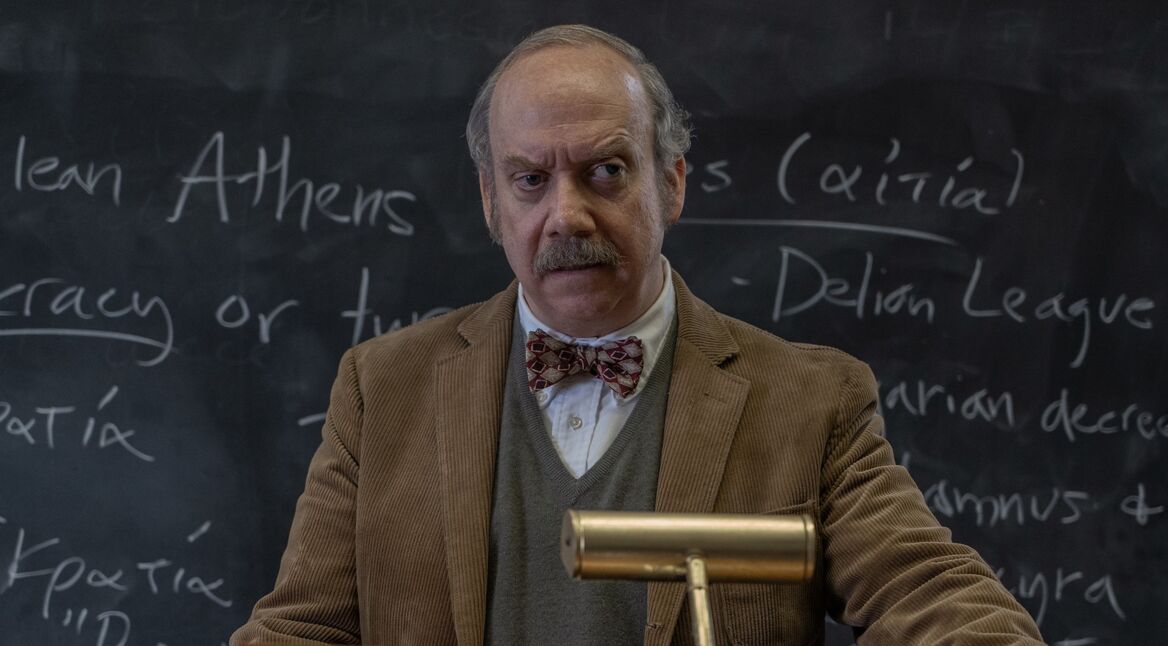 Ein Lehrer steht am Pult vor einer Tafel.