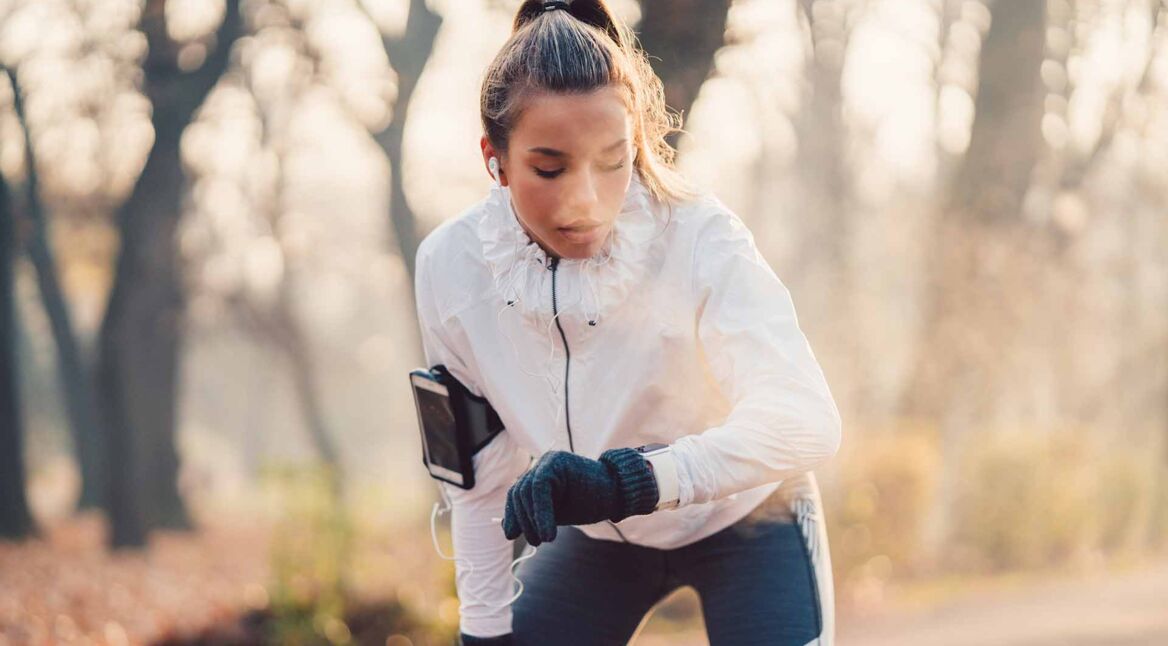 Eine Sportlerin checkt ihre Smartwatch beim Joggen