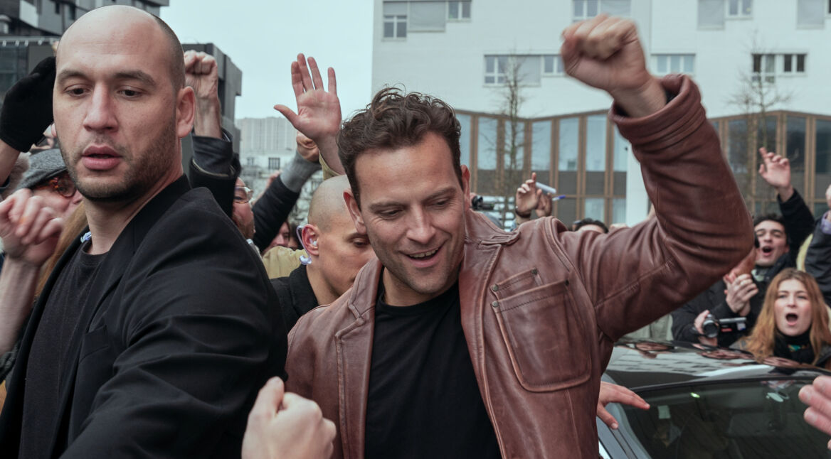 Supersex: Der Schauspieler Alessandro Borghi als Rocco Siffredi, wie er aus dem Auto steigt und dabei die Hand nach oben hebt.