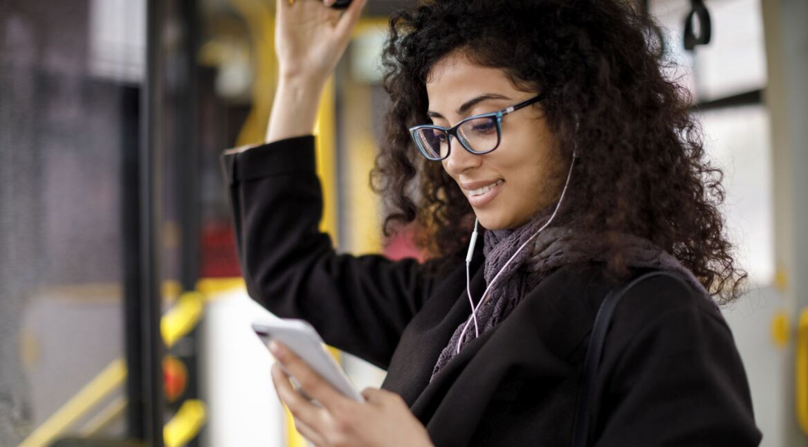 Frau schaut im Bus auf ihr Smartphone