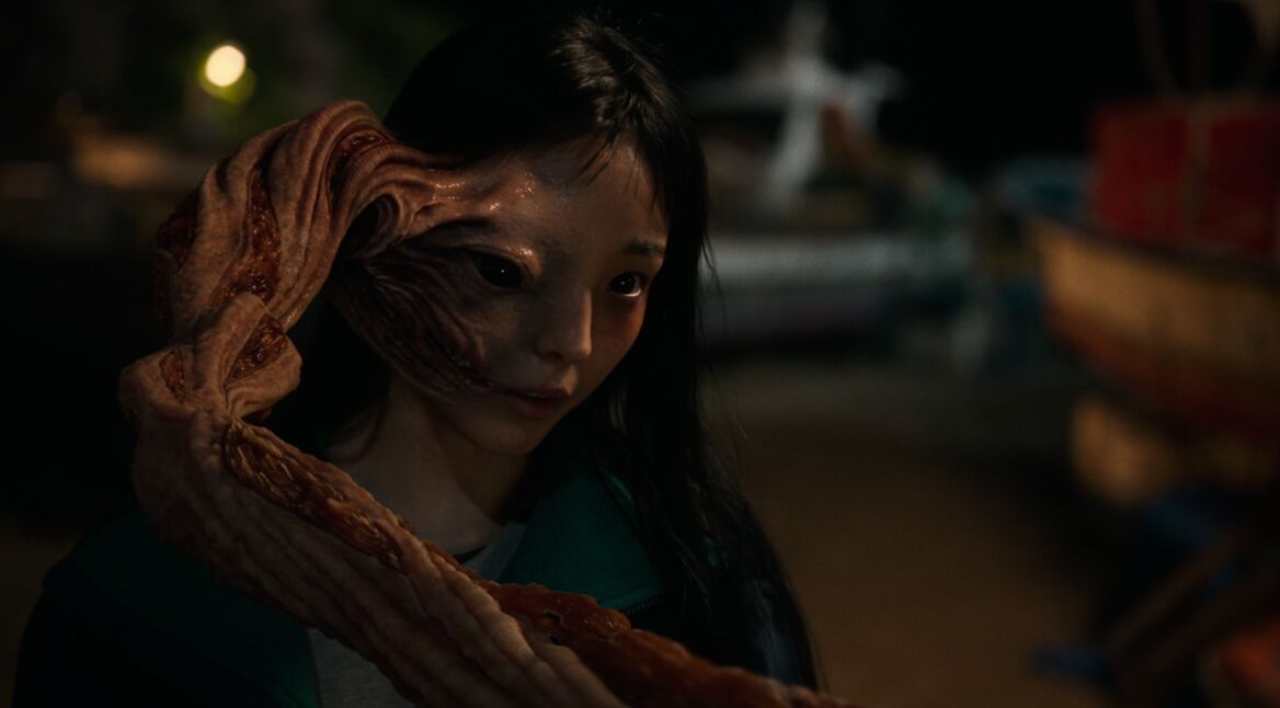 Eine junge Frau mit einem außerirdischen Lebewesen am Kopf