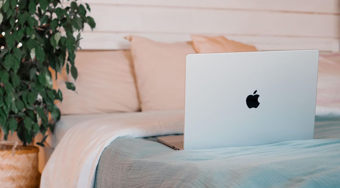 Apple MacBook liegt aufgeklappt auf einem Bett.