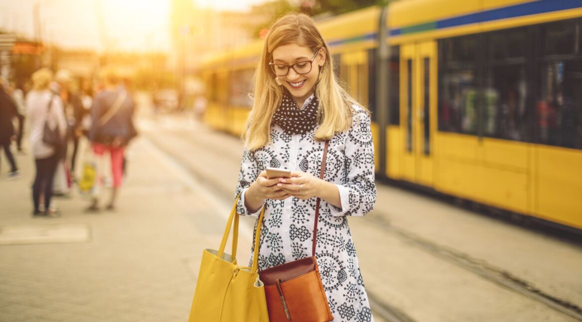 Frau schaut während des Stadtbummels auf ihr Samsung-Handy.
