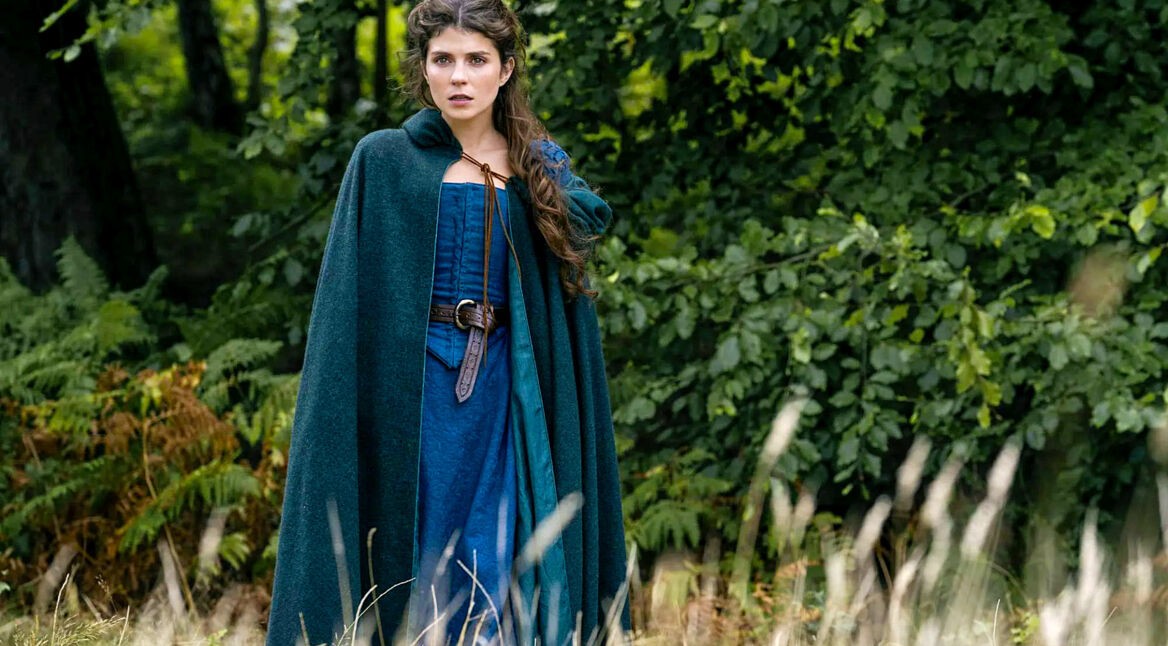 Lady Jane steht in einem blaugrünen Gewand auf einem Feld.