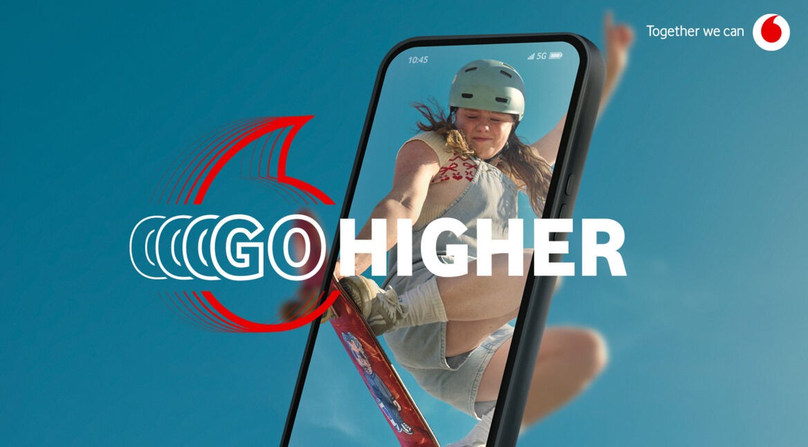 Auf diesem BIld zur neuen Vodafone-Go-Kampagne ist ein junges Mädchen auf einem Skateboard zu sehen. Sie springt vom Smartphone in die reale Welt. Darüber liegt der Text "Go Higher" vor blauem Hintergrund. Das Bild so ausdrücken, dass man seine Leidenschaften starten und teilen soll.