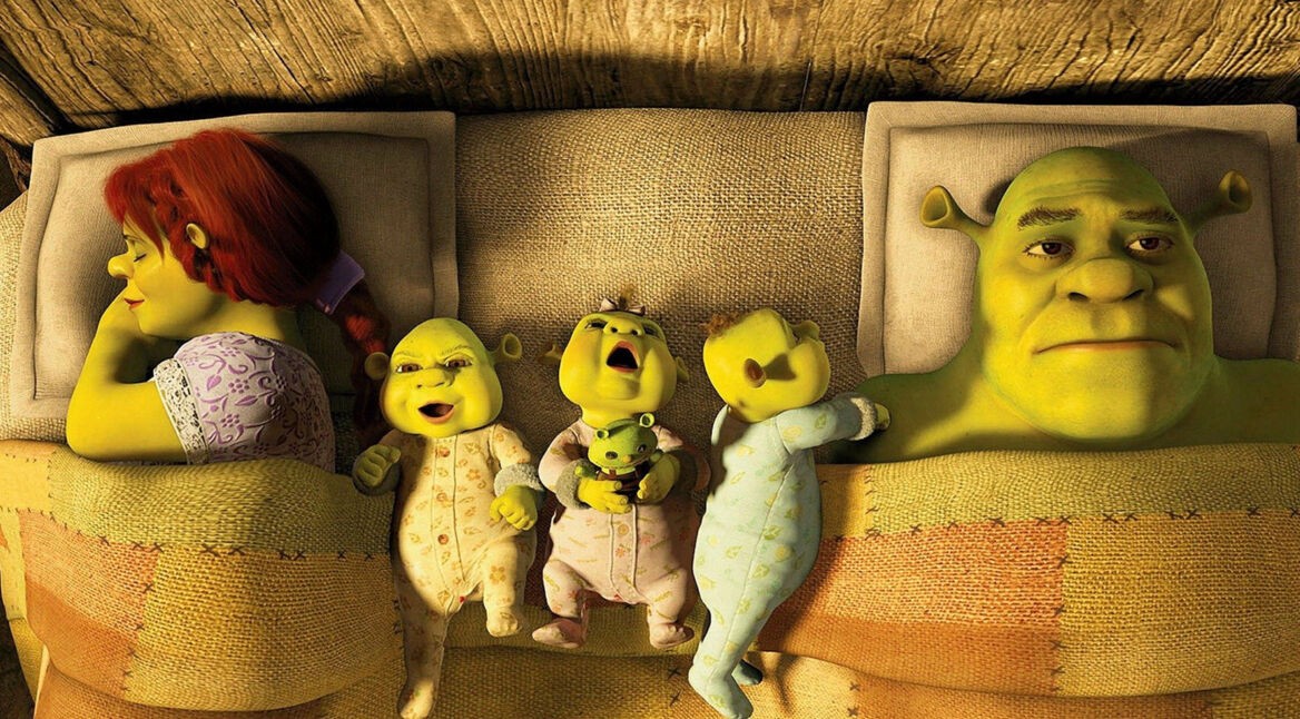 Auf dem Bild ist eine Oger-Familie zu sehen, die im Bett liegt. Links liegt Fiona und recht Shrek. Sie sind die Hauptfiguren aus dem Shrek-Franchise. Zwischen ihnen liegen 3 kliene Oger-Babys. Eins lacht, eins schreit und eins schaut seinen Vater, also Shrek, mit erwartungsvollem, spielerischen Blick an. Shrek starrt an die Decke und wirkt nicht sonderlich zufrieden mit der Situation. Er sieht aus, als würde er sich einfach seinem Familienschicksal ergeben. Fiona hingegen liegt auf der Seite, mit dem Gesicht weg von Shrek. Sie schläft und lächelt dabei zufrieden.