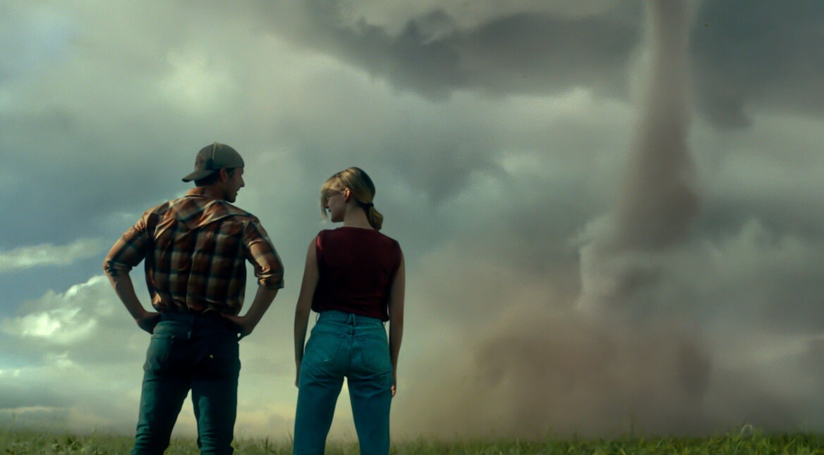 Ein Mann und eine Frau stehen vor einer Tornadowolke.