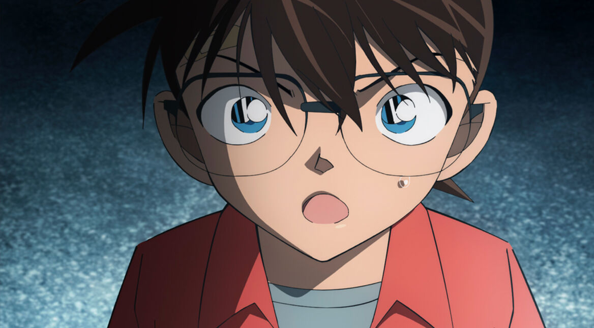 Im Bild im Artikel zum Kinofilm Detektiv Conan Film 27: Das 1-Million-Dollar-Pentagramm ist das Gesicht und die Schultern der Figur Detektiv Conan zu sehen. Der animierte Charakter schaut mit großen blauen Augen in die Kamera. Die dunkelbraunen Haare fallen ihm ins Gesicht. Seine Augenbrauen sind zusammengezogen, als wäre er wütend. Sein Mund ist geöfnet, als würde er gerade auf sein Gegenüber einreden. Dieses Gegenüber ist scheinbar viel größer als er, denn sein Kopf und sein Blick sind nach oben geneigt. Er trägt ein korallrotes Hemd und darunter ein graues T-Shirt.