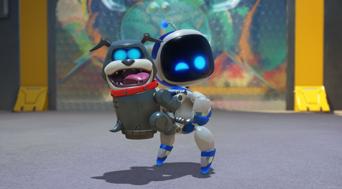 Auf dem Bild aus Astro Bot Test hält der kleine Roboter Astro Bot einen fröhlich aussehenden Roboter-Hund in seinen Armen. Beide haben leuchtend blaue Augen und wirken zufrieden. Der Hintergrund zeigt eine farbenfrohe, unscharfe Wand in einer futuristischen Umgebung. Astro Bot scheint sich auf einen spielerischen Moment zu freuen, während der Roboter-Hund mit offenem Mund glücklich aussieht. Die Szene wirkt freundlich und energiegeladen.