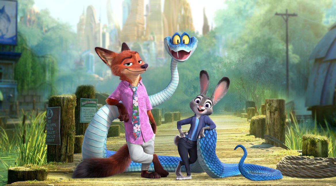 Auf dem Bild zu Zoomania 2 stehen drei tierische Charaktere im Fokus: Ein selbstbewusst wirkender Fuchs in Hawaiihemd, eine fröhlich lächelnde Häsin in Polizeiuniform und eine blaue Schlange mit großen gelben Augen. Die Szenerie spielt auf einem Holzsteg vor grüner Landschaft.