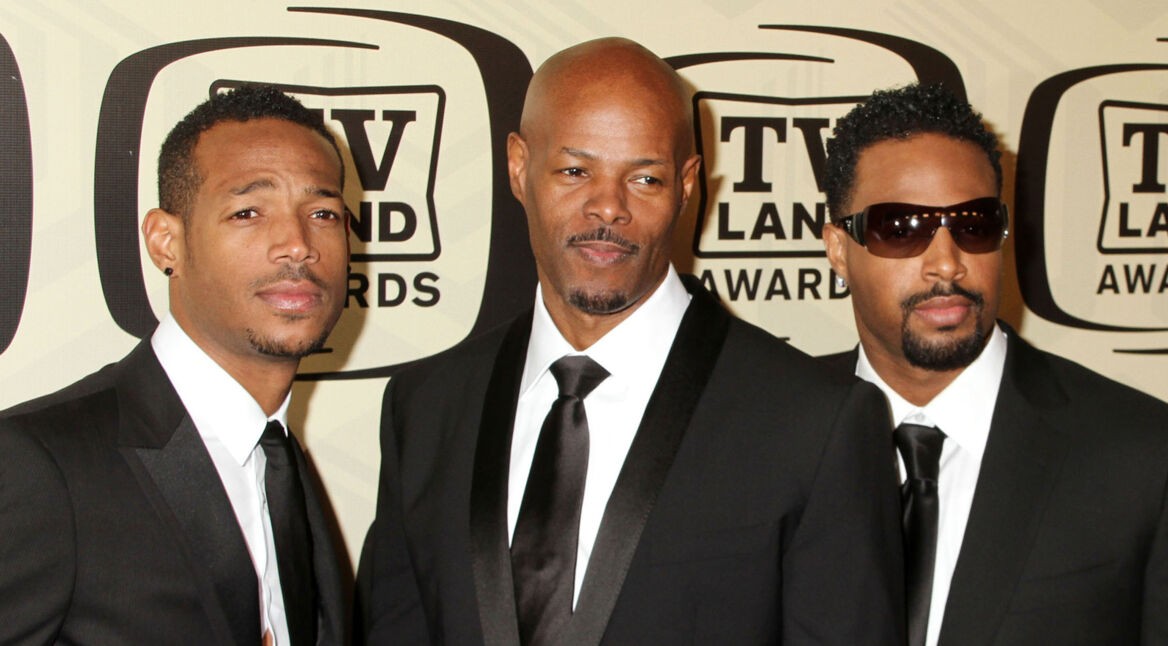 Auf dem Bild zum neuen Scary Movie Film sind die drei Wayans Brüder zu sehen, die in dunklen Anzügen vor einer TV Land Awards Wand posieren. Links steht Marlon Wayans mit leichtem Lächeln, in der Mitte Keenen Ivory Wayans mit kühlem Blick, und rechts Shawn Wayans mit Sonnenbrille. Die Brüder wirken stilvoll und selbstbewusst.
