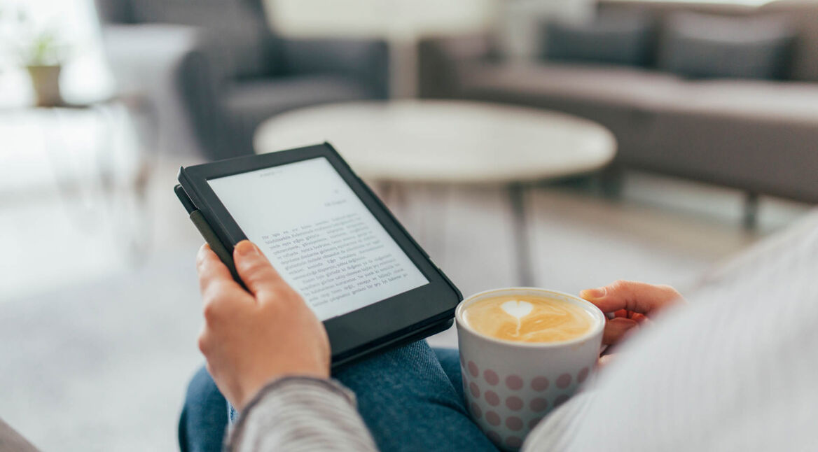 Ein E-Book-Reader in den Händler einer Frau, die auf der Couch liest