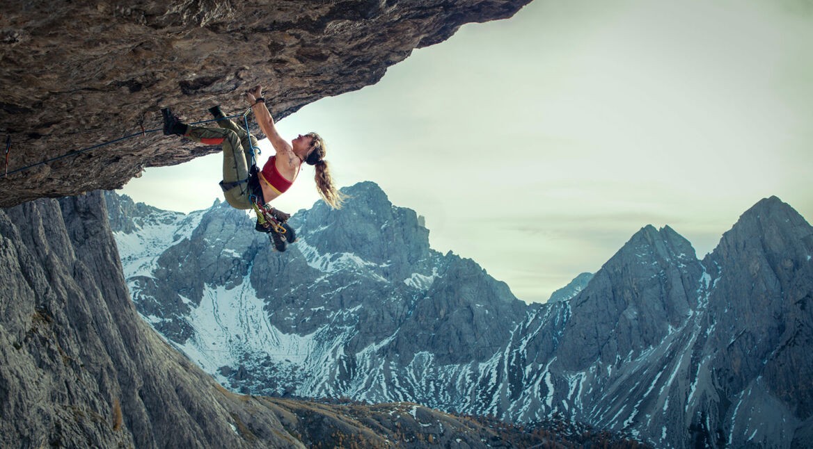 Auf dem Bild im Artikel über das Cliffhanger-Reboot ist zu sehen, wie die Schauspielerin Lily James an einem Berg klettert. Im Hintergrund sind weitere Berge zu sehen.