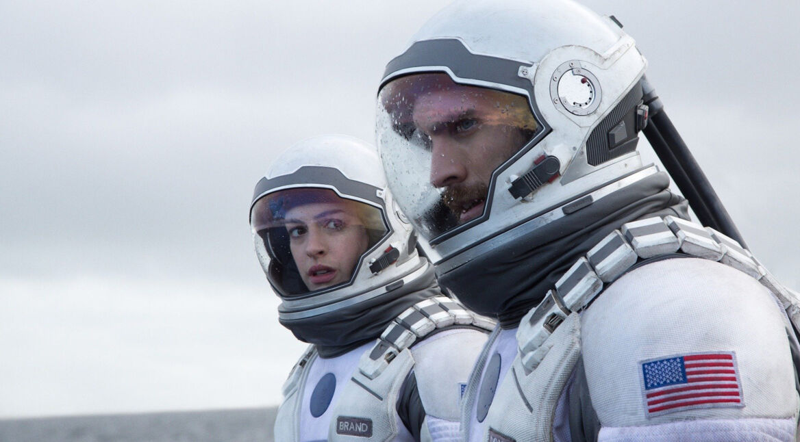 Auf diesem Bild zu Interstellar Fakten sind die Charaktere Amelia Brand und Cooper in ihren Raumanzügen zu sehen, gespielt von Anne Hathaway und Matthew McConaughey. Beide blicken konzentriert in die Ferne, während Regentropfen auf ihren Helmen zu sehen sind. Die Szene wirkt angespannt und ernst, passend zur Atmosphäre des Films, der Themen wie Raumfahrt und Überlebenskampf behandelt.