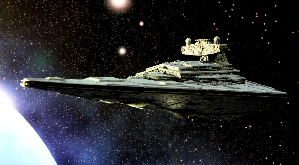 Auf dem Bild in dem Artikel über die neue Star Wars-Trilogie ist ein Raumschiff zu sehen, welches im Weltraum schwebt. Im Hintergrund sieht man die Lichter des Weltalls auf einem dunklen Hintergrund.