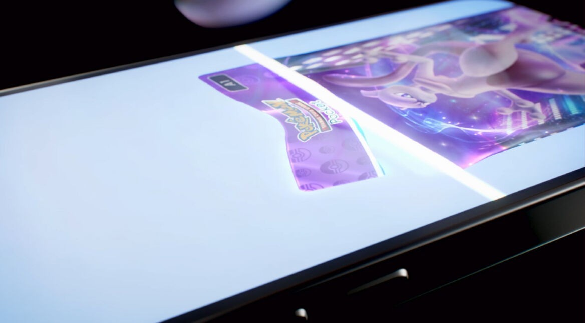 Auf dem Bild zu dem Artikel über die Pokémon TCG Pocket Tipps ist ein Smartphone-Display zu sehen, auf dem eine holografische Pokémon-Karte erscheint. Die Karte schimmert in violettem Licht, während das Logo von Pokémon Trading Card Game hervorgehoben ist. Das Smartphone liegt leicht angewinkelt auf einer dunklen Oberfläche, wodurch der futuristische Effekt der Darstellung betont wird.
