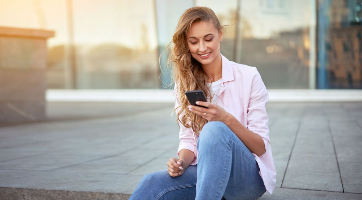 Junge Frau schaut auf ihr Handy.