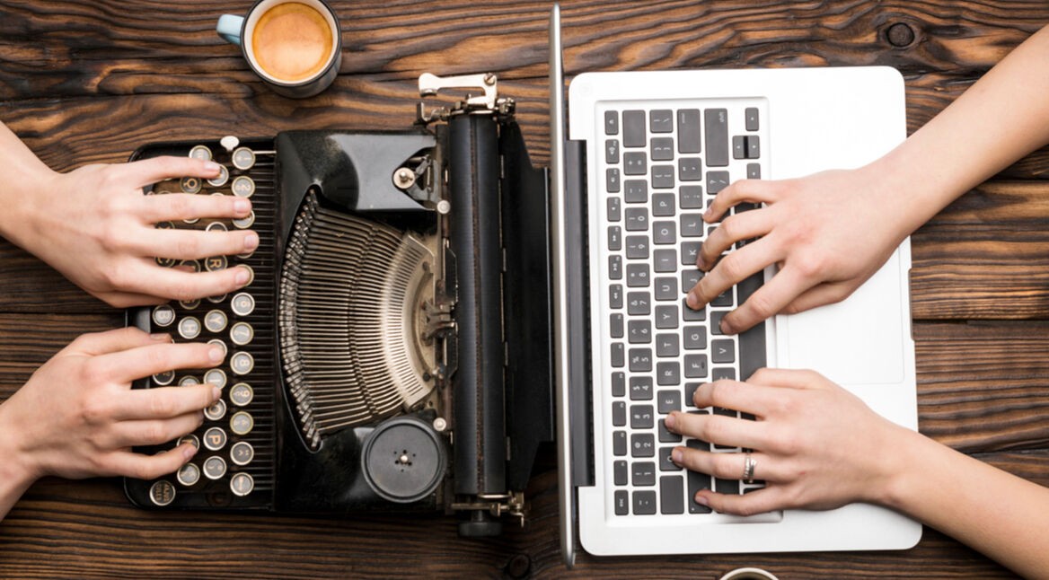 Das Bild zeigt einen Vergleich zwischen alt und neu: Links wird auf einer klassischen Schreibmaschine, einem typischen Retro-Gadget, getippt, während rechts ein moderner Laptop genutzt wird. Beide Geräte stehen nebeneinander auf einem Holztisch, was den Kontrast zwischen analogem und digitalem Arbeiten verdeutlicht.