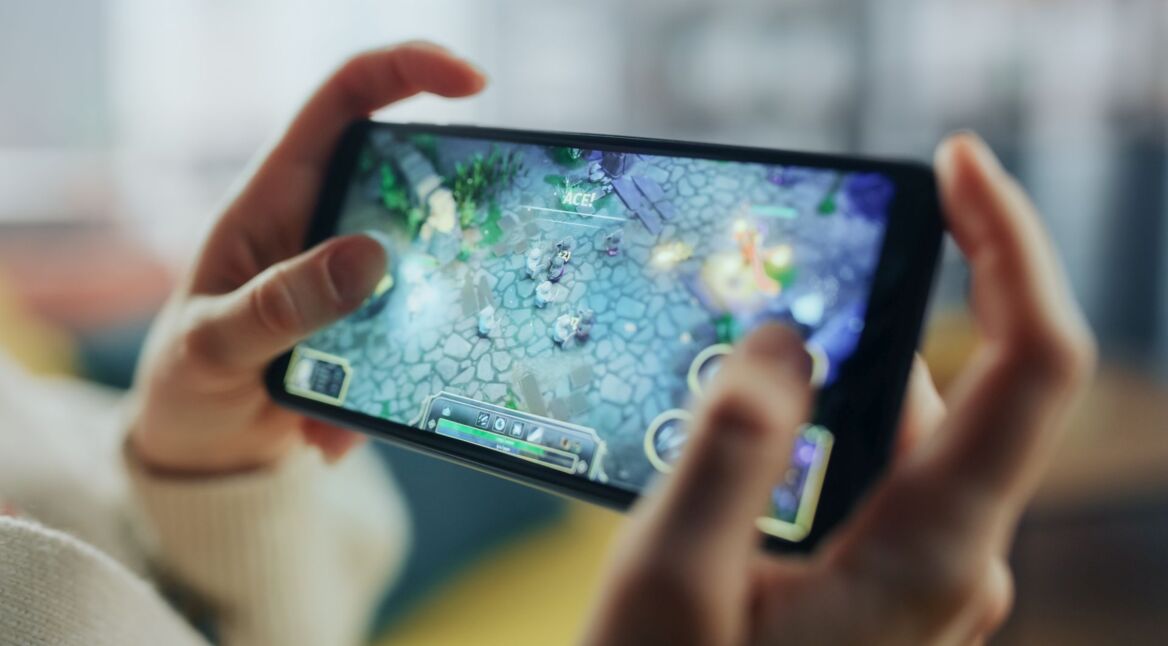 Zwei Hände halten ein Smartphone im Landscape-Modus, darauf läuft ein Mobile Game.