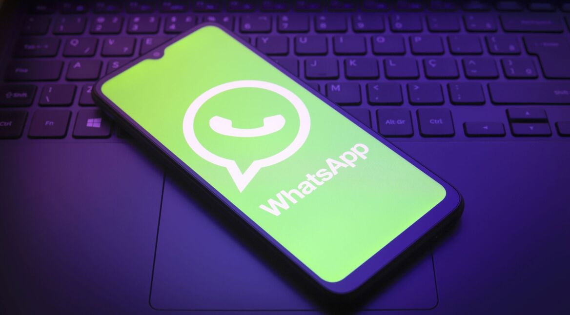 Ein Smartphone, auf dem das Logo von WhatsApp abgebildet ist, liegt auf einer Laptop-Tastatur.