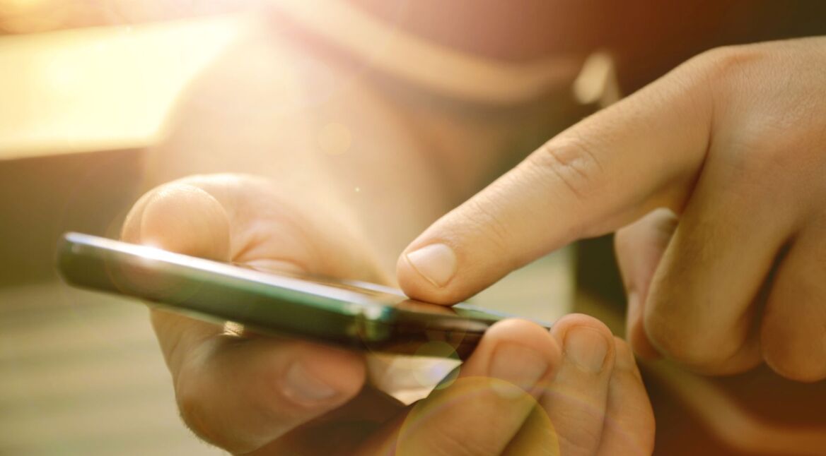 Mit dem Finger auf das Display eines Smartphones tippen.