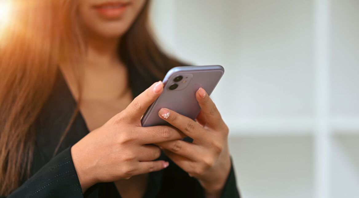 Junge Frau hält ein iPhone in ihren Händen