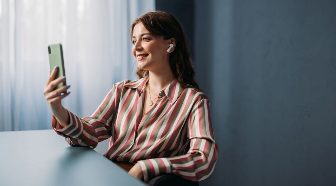 Junge Frau nimmt ein Video von sich mit ihrem Smartphone auf.