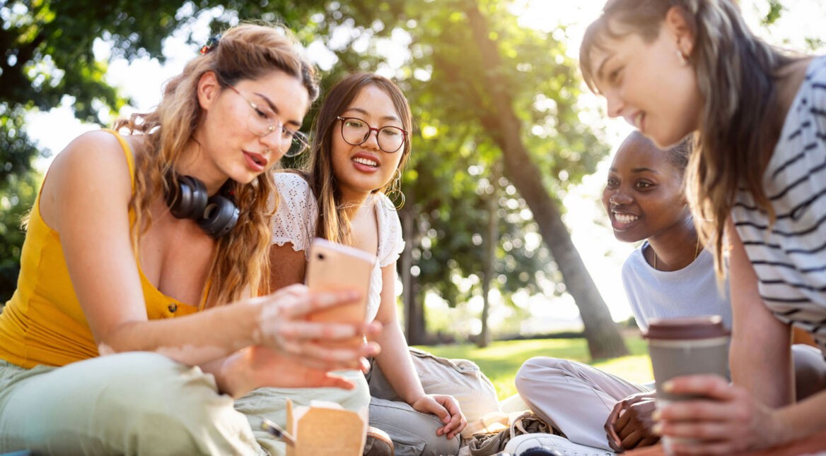 Eine Gruppe junger Frauen schaut fröhlich auf ein Smartphone.