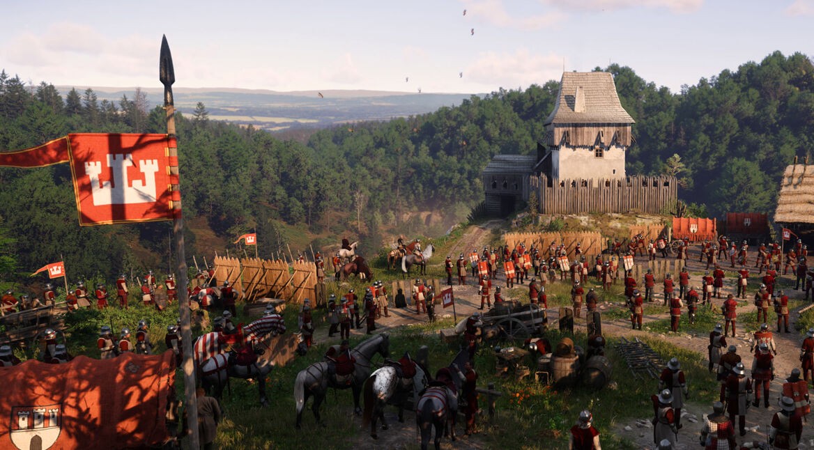 Auf dem Bild in dem Artikel zum Kingdom Come: Deliverance 2 Test ist ein mittelalterliches Militärlager vor einer hölzernen Festung zu sehen. Zahlreiche Soldaten in roten Wappenröcken und Metallhelmen stehen in Formation. Fahnen mit einem Wappen aus weißen Türmen auf rotem Grund wehen im Wind. Im Hintergrund erstreckt sich eine grüne Hügellandschaft unter einem klaren Himmel. Die Szene wirkt lebendig und strategisch angespannt.