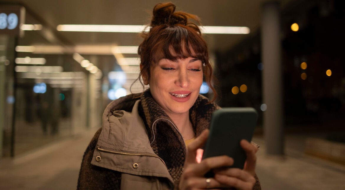 Eine junge Frau hält ein Smartphone in den Händen.