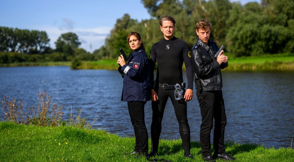 Süher Özlügül (Sophie Dal), Wolfgang Habedank (Holger Stockhaus) und Henk Cassens (Maxim Mehmet) stehen am Emsufer.
