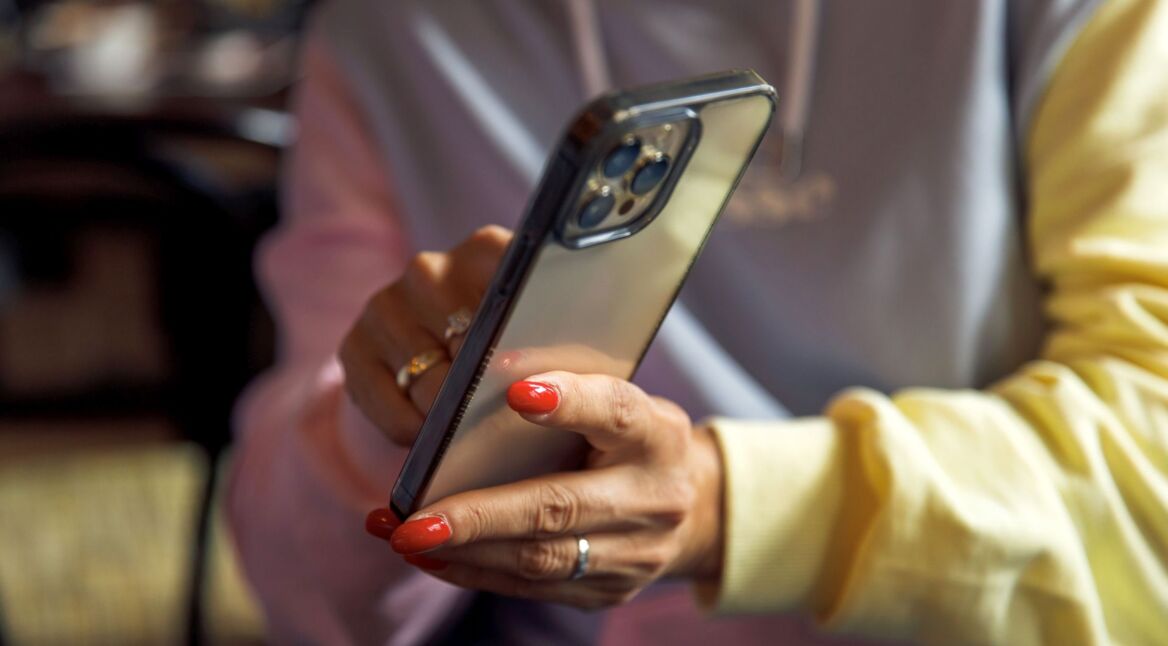Frau zeigt mit ihrer Hand auf etwas auf dem iPhone.